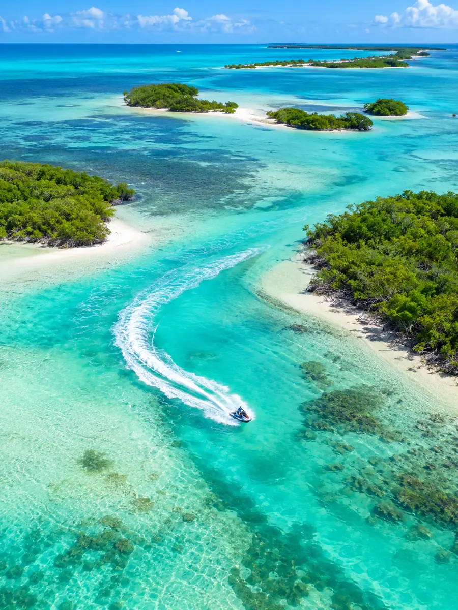 Luftaufnahme einer Jetski-Spur über türkisfarbenen Flachwasserflächen und Mangroveninseln in den Florida Keys
